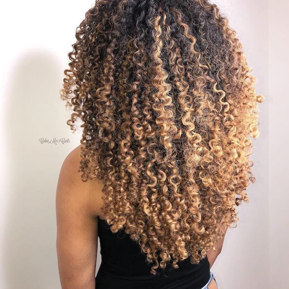 Hinterkopf einer Frau mit blondem Balayage durch lockiges Haar, kreiert mit Wella Professionals