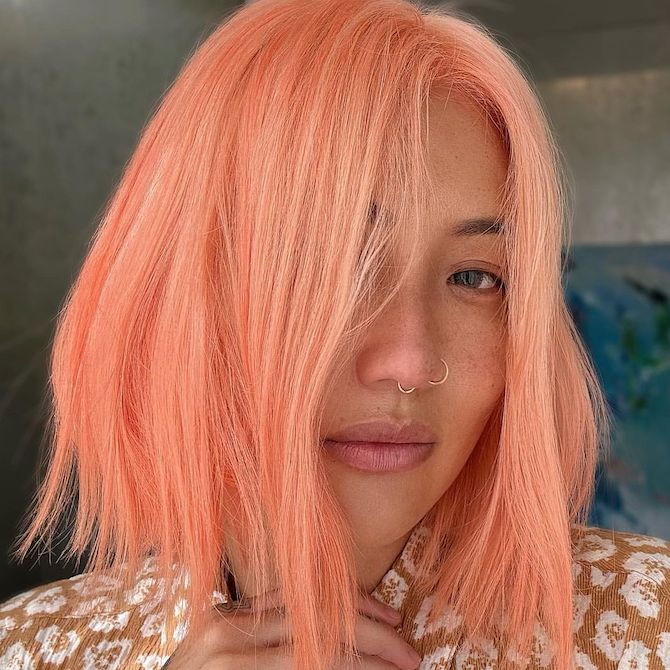 Model with shoulder-length bob haircut in a bright peach blonde shade.
