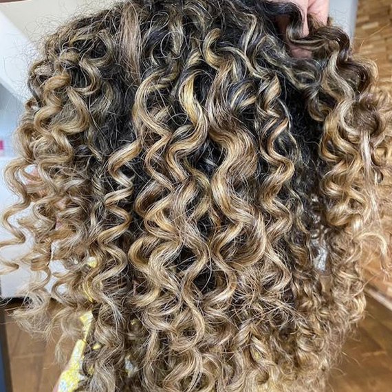 Seitenprofil einer Frau mit blondem, lockigem Haar, kreiert mit Wella Professionals.