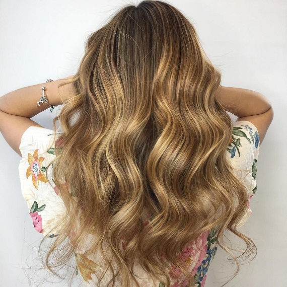 Hinterkopf einer Frau mit langem, gewelltem, goldenem Toffee-Haar, kreiert mit Wella Professionals.