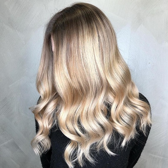 Frau mit cremefarbenem, blondem Haar, kreiert mit Wella Professionals.