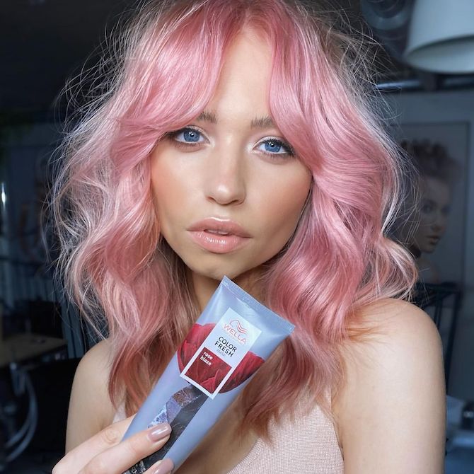 Model with wavy, candy pink hair holds up Color Fresh Mask in Rose Blaze.