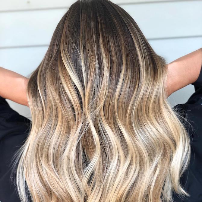 Frau mit langem, gewelltem, rooted-blonde Hair, kreiert mit Wella Professionals.
