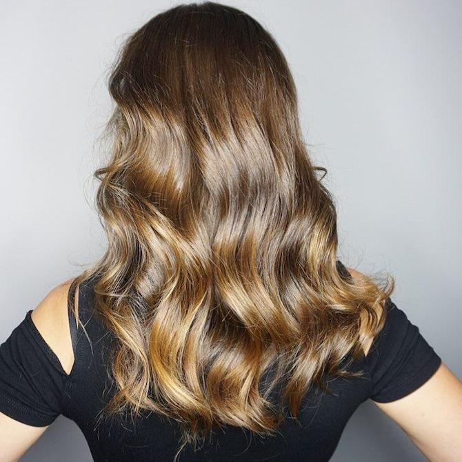 Back of woman’s head with long, wavy, glossy brunette hair, created using Wella Professionals.