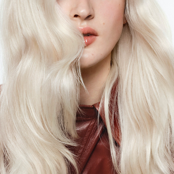 Close-up of the lengths and ends of a model’s icy blonde, wavy hair.