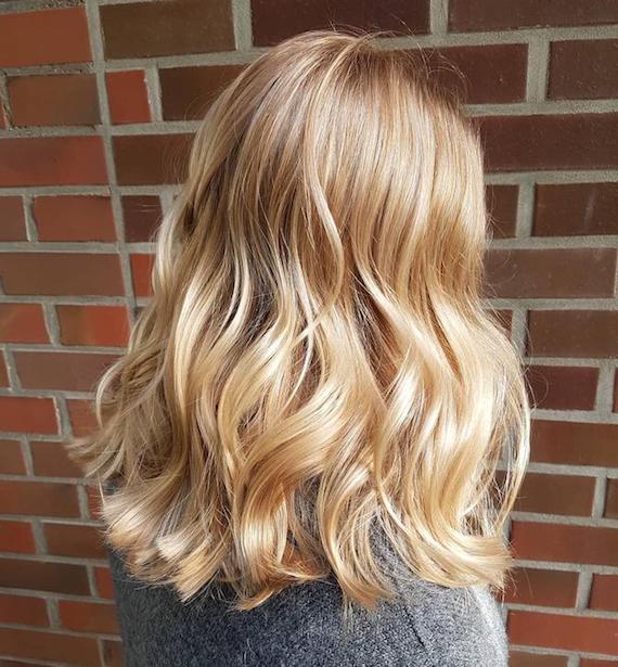Foto des Hinterkopfes einer Frau mit gewelltem goldblondem Haar, kreiert mit Wella Professionals