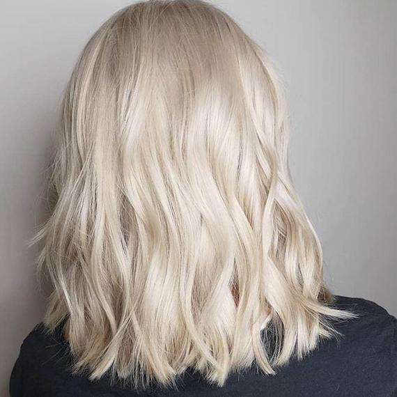 Foto des Hinterkopfes einer Frau mit gewelltem cremeblondem Haar, kreiert mit Wella Professionals.