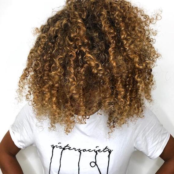 Woman with bronde highlights through curly hair, created using Wella Professionals