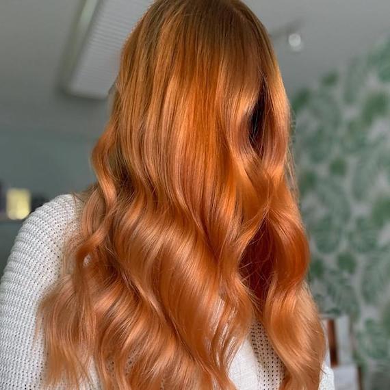 Woman with long, wavy, warm blorange hair falling past her shoulders.