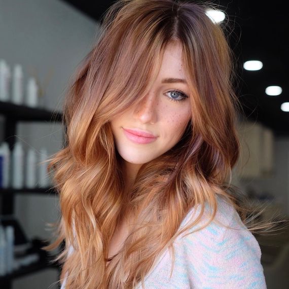 Model with tousled, dark cinnamon blonde hair faces the camera.