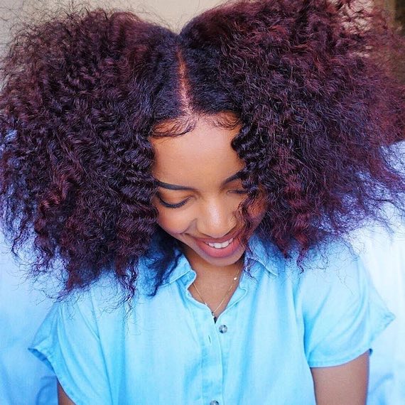 Model with type 4A curly hair glances down.