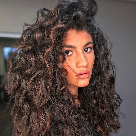 Model with type 2B wavy hair faces camera.