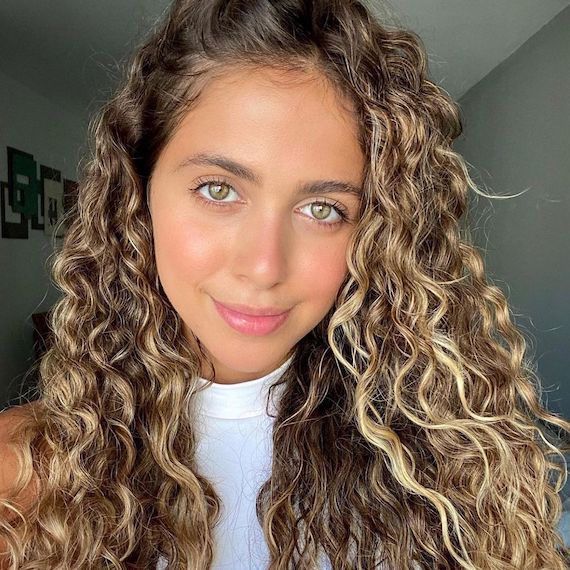 Model with type 2C wavy hair faces camera.