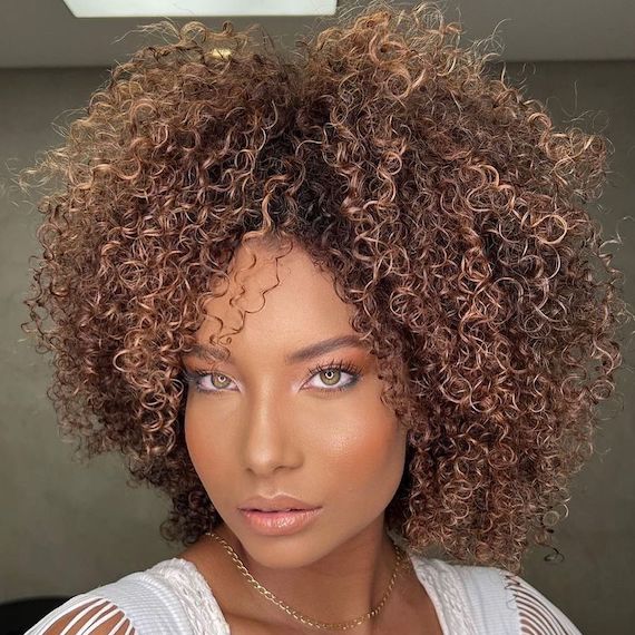 Model with type 3C curly hair faces camera.