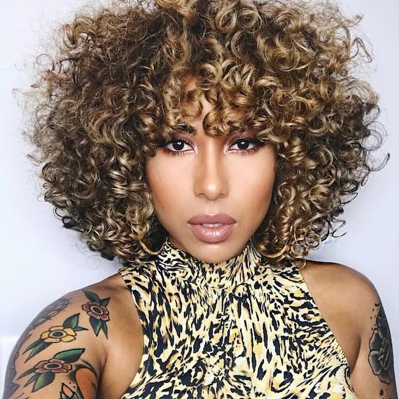 Model with type 3B curly hair faces camera.