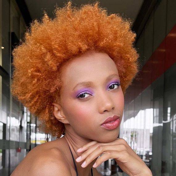 Model with type 4C curly hair faces camera.