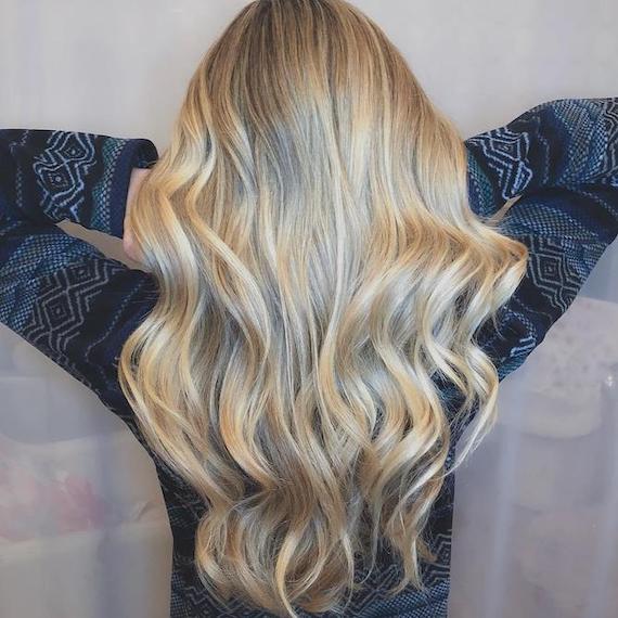 Hinterkopf einer Frau mit langem, gewelltem, blondem Haar, erstellt mit Wella Professionals.