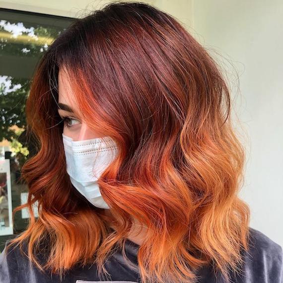 Side profile of woman with red ombre hair and a fiery money-piece.