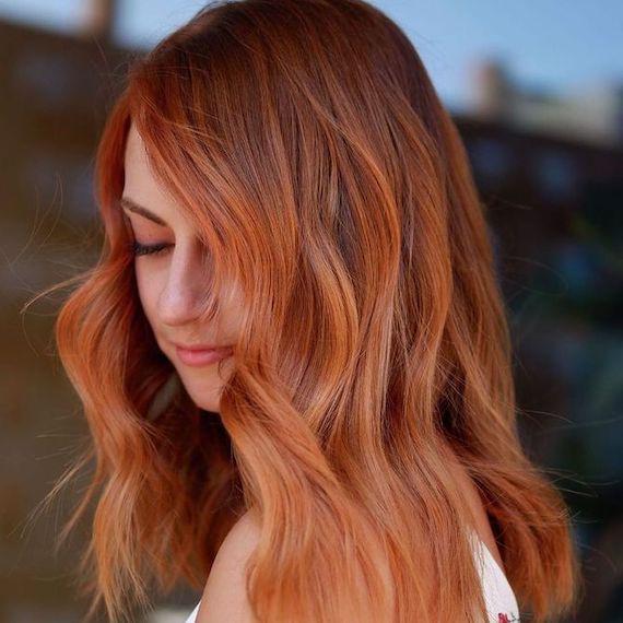 Model with tousled copper hair and peachy highlights.
