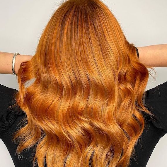 Model mit hellrotem Haar, das in lockeren Wellen gestylt ist.
