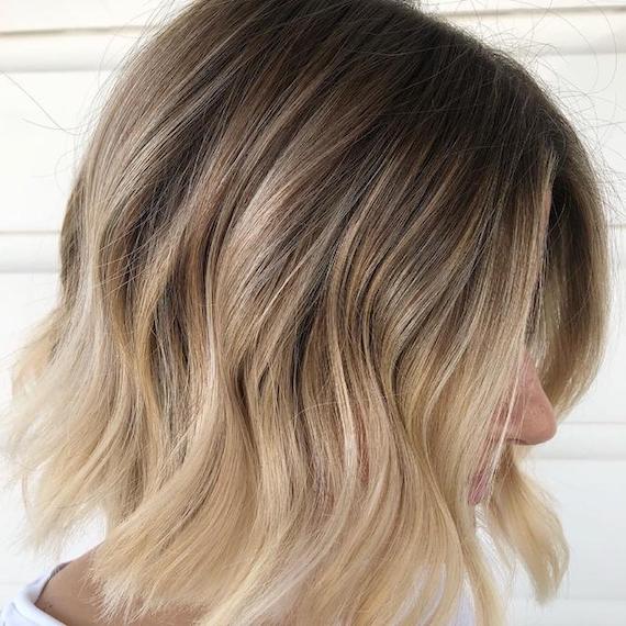Seitenprofil einer Frau mit gewelltem, blondem Ombré-Bob.