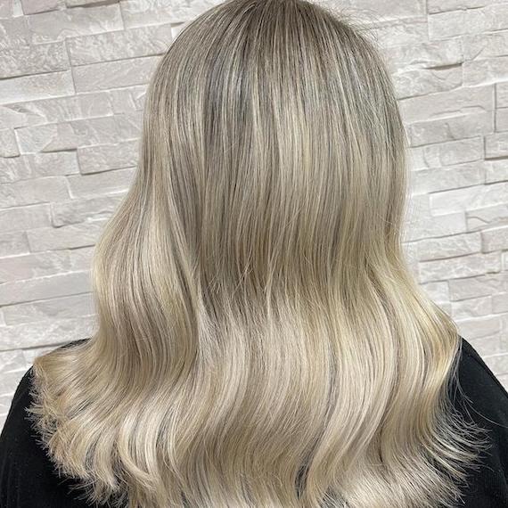 Hinterkopf einer Frau mit mittellangem, locker gewelltem, blondem Haar.