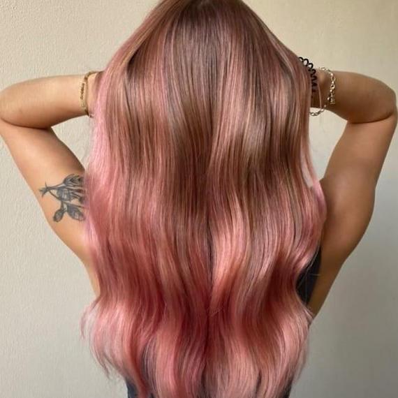 Hinterkopf einer Frau mit langem, gewelltem Haar und rosa Balayage.