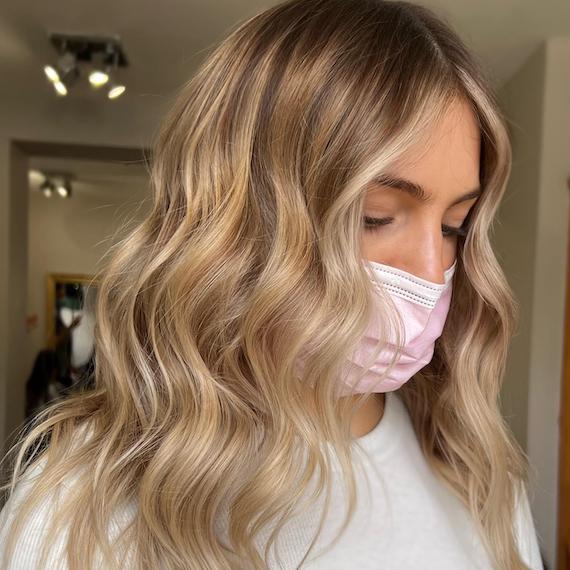 Eine Frau blickt nach unten und zeigt ihr gewelltes, blondes Haar.