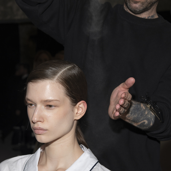 Anthony Turner sprays model’s finished sleek ponytail with hairspray.