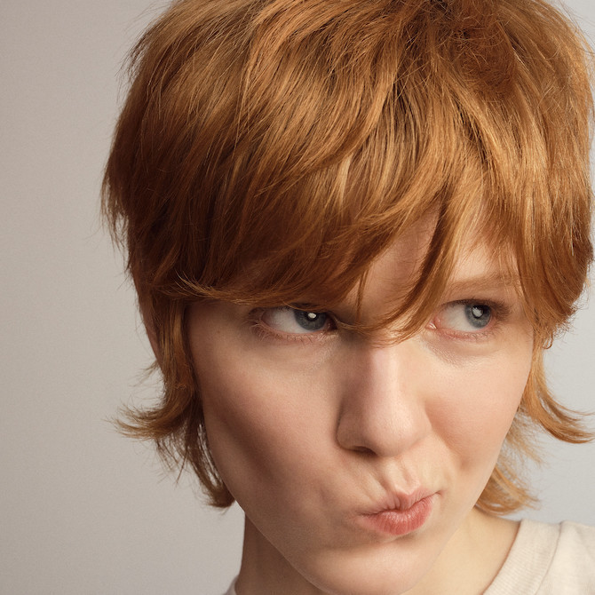 Model with short, strawberry blonde hair featuring bangs.