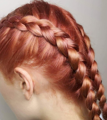 Model with peach hair styled into two braids, created with Blondor and Koleston Perfect