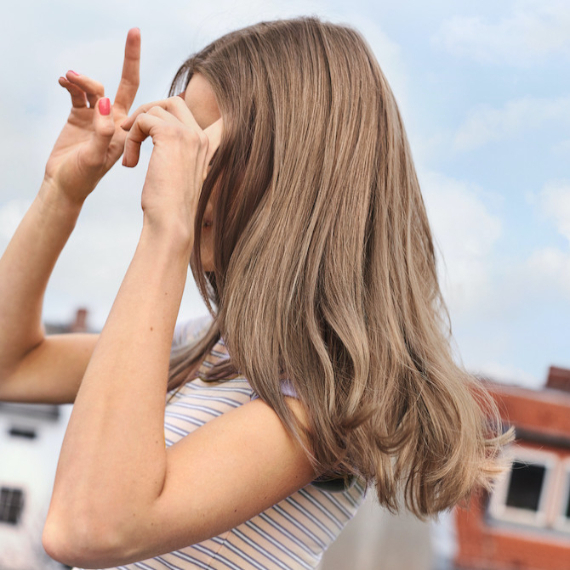 Seitenprofil einer Frau mit langem, glänzendem, aschbraunem Haar, kreiert mit Wella Shinefinity.