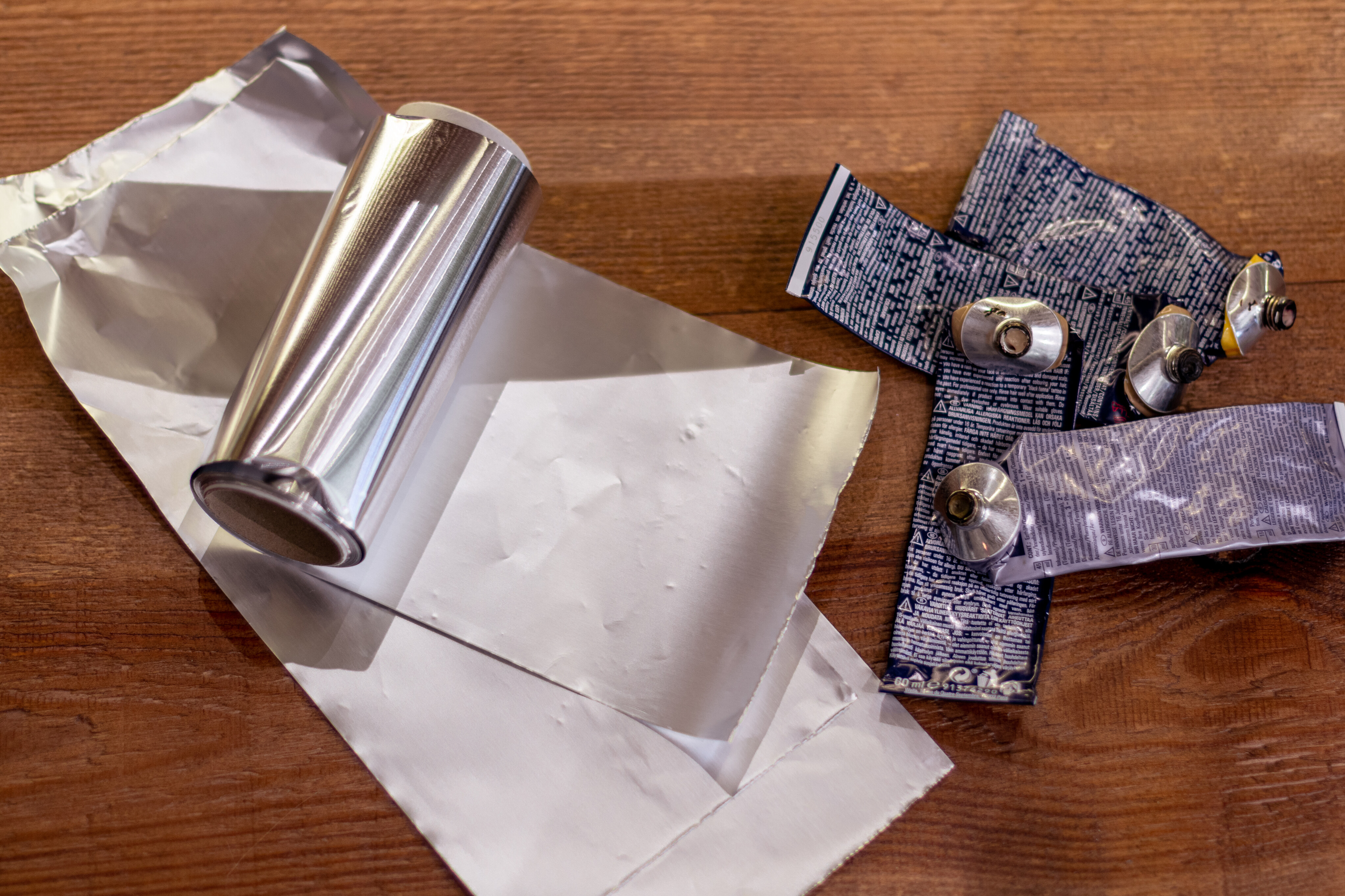 Mehrere leere Tuben Koleston Perfect von Wella Professionals und eine Aluminiumfolie liegen nebeneinander.