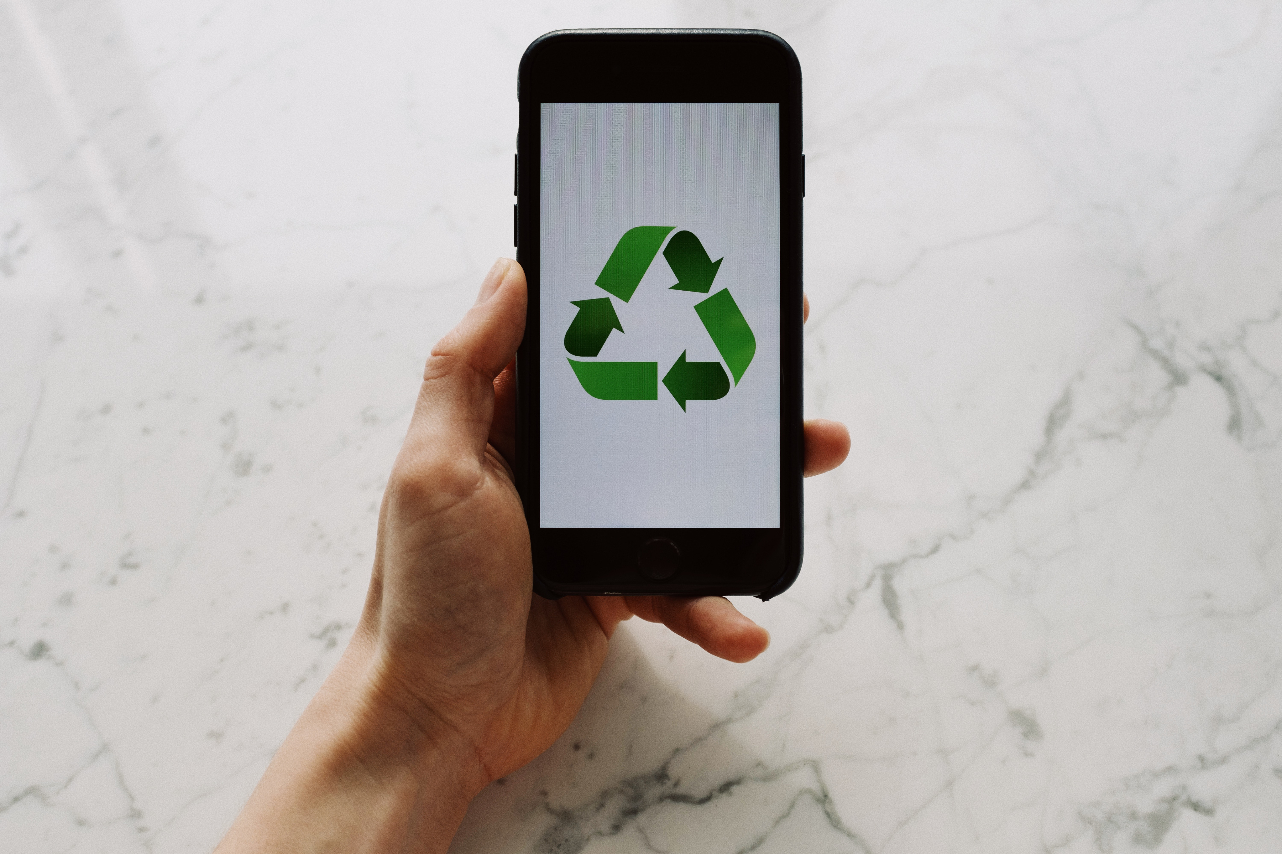 Handy mit grünem Recycling Symbol.