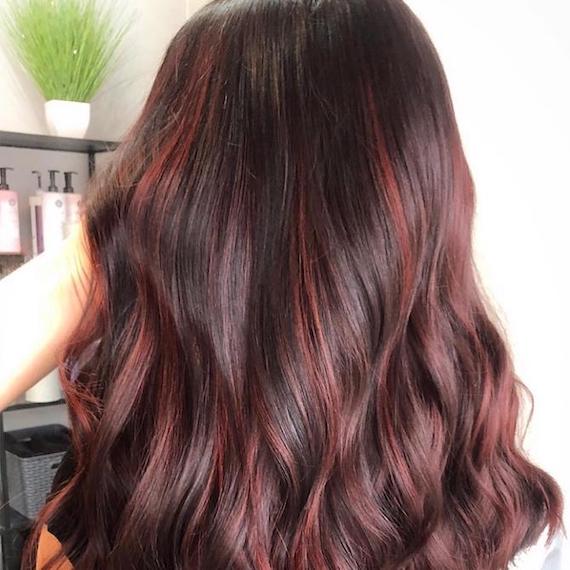 Hinterkopf einer Frau mit langem, gewelltem, schokobraunem Haar, kreiert mit Wella Professionals.