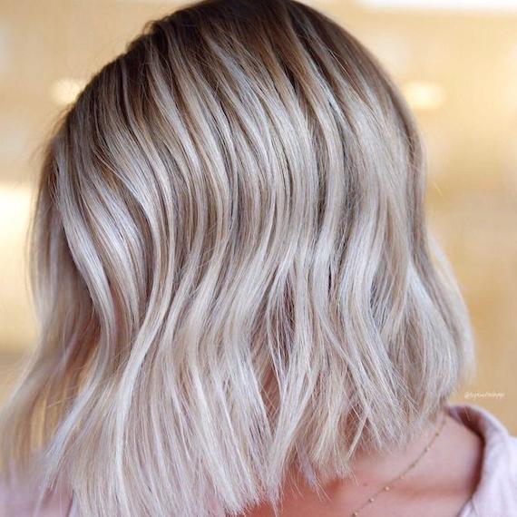 Seitenprofil einer Frau mit platinblondem Haar und dunklerem Ansatz, kreiert mit Wella Professionals.