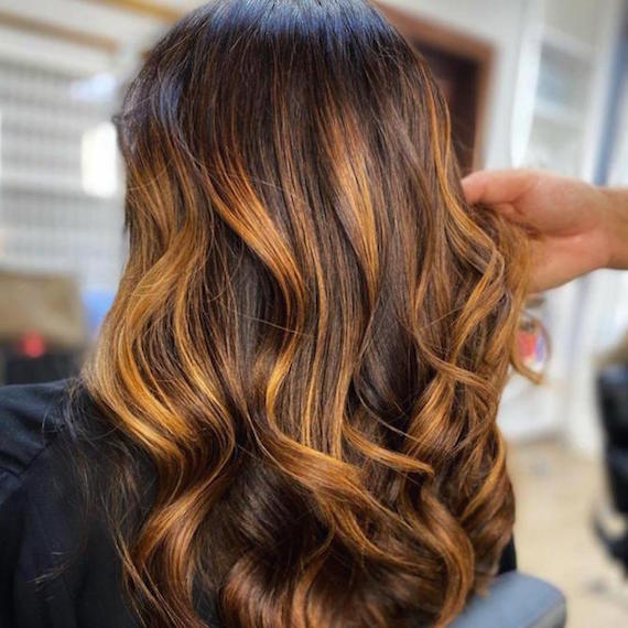 Hinterkopf einer Frau mit kupferfarbenen Strähnchen im braunen Haar, kreiert mit Wella Professionals.