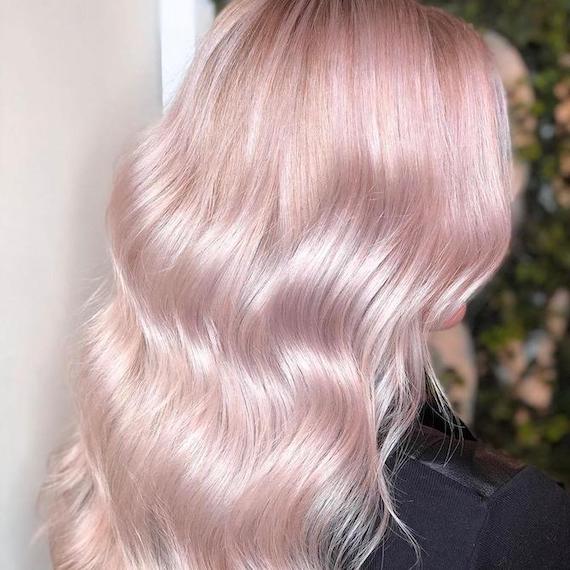 Hinterkopf einer Frau mit gewelltem, pastellrosa Haar, kreiert mit Wella Professionals.