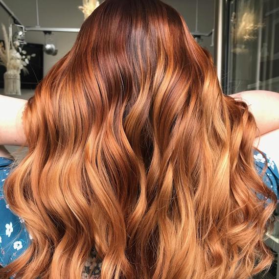 Back of woman’s head with long, wavy, auburn blonde hair.