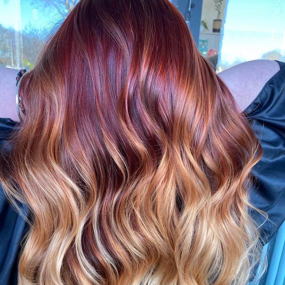 Back of woman’s head with wavy, tousled, auburn and blonde, dip-dyed hair.
