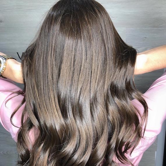 Back of woman’s head with long, dark brown hair and babylights, created using Wella Professionals.