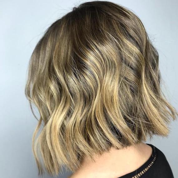 Seitenprofil einer Frau mit dirty-blondem Balayage durch einen gewellten Bob, kreiert mit Wella Professionals.