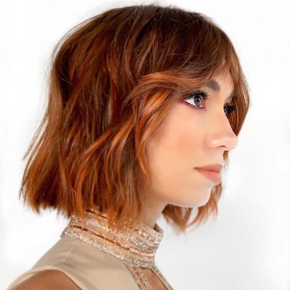 Foto einer Frau mit gewelltem Kupfer-Balayage-Bob, kreiert mit Wella Professionals.