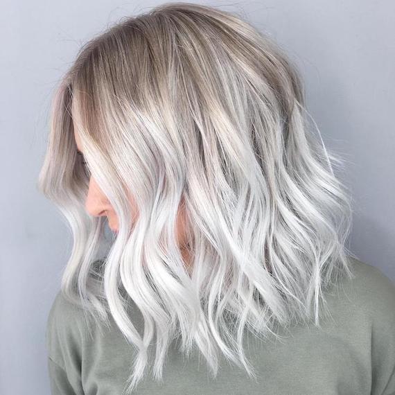 Seitenprofil einer Frau mit eisblondem Balayage durch einen langen Bob, kreiert mit Wella Professionals.