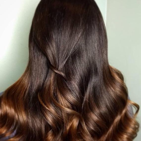 Model with long, wavy hair and dark brown balayage, created using Wella Professionals.