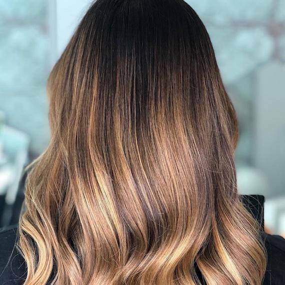 Model with long, wavy hair and dark blonde balayage, created using Wella Professionals.