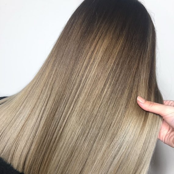 Back of woman’s head with ash bronde balayage through straight hair, created using Wella Professionals.