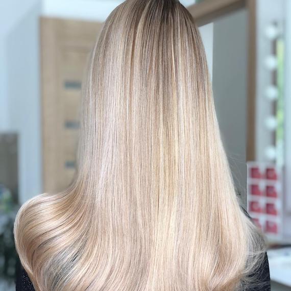 Back of woman’s head with vanilla blonde balayage through straight hair, created using Wella Professionals.
