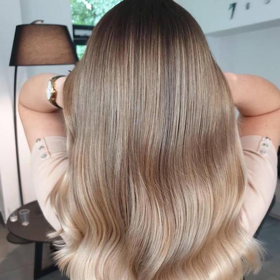 Back of woman’s head with cool blonde balayage through straight hair, created using Wella Professionals.