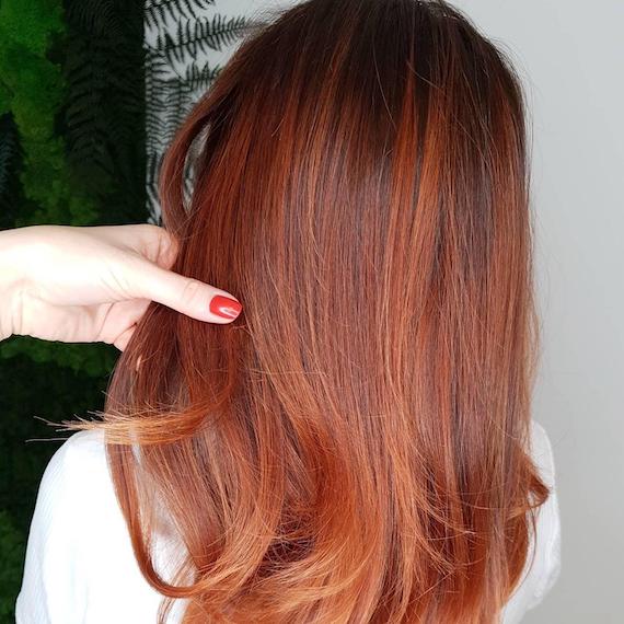 Back of woman’s head with auburn balayage through straight hair, created using Wella Professionals.